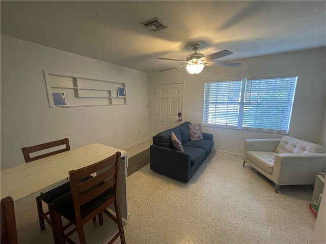 living room with a textured ceiling and ceiling fan