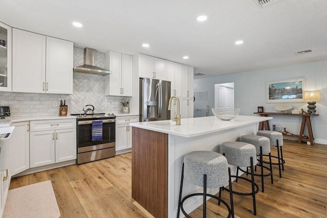 9830 Oak Trl, Sebastian, FL 32976 - kitchen with stainless steel appliances, wall chimney range hood, white cabinets, and recessed lighting
