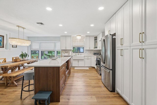 9830 Oak Trl, Sebastian, FL 32976 - kitchen with appliances with stainless steel finishes, light countertops, a breakfast bar, a center island with sink, and white cabinetry