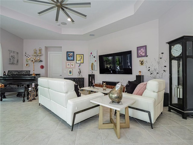 tiled living room featuring ceiling fan and a raised ceiling