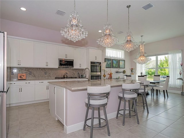 kitchen with pendant lighting, white cabinets, a spacious island, and appliances with stainless steel finishes