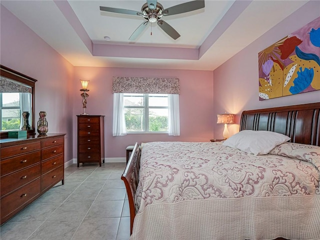 tiled bedroom with ceiling fan and a raised ceiling