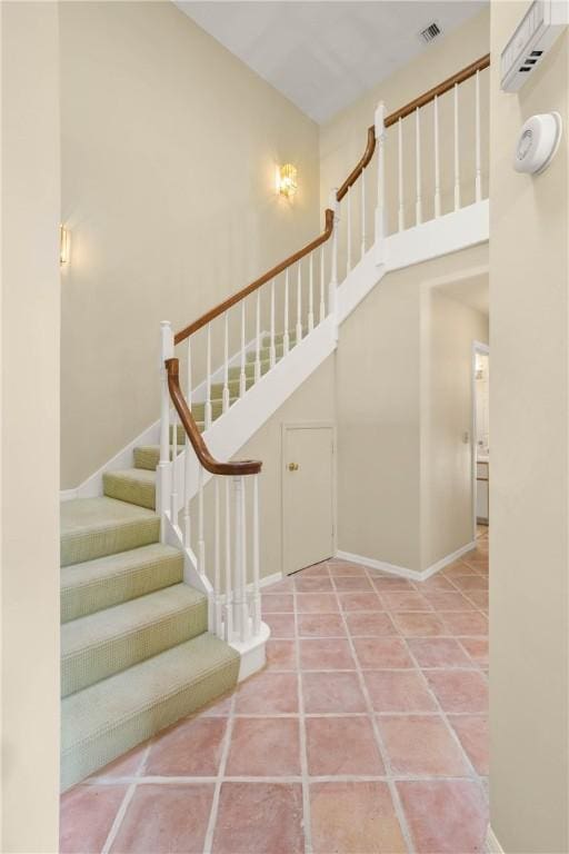 stairs featuring a towering ceiling and tile patterned flooring