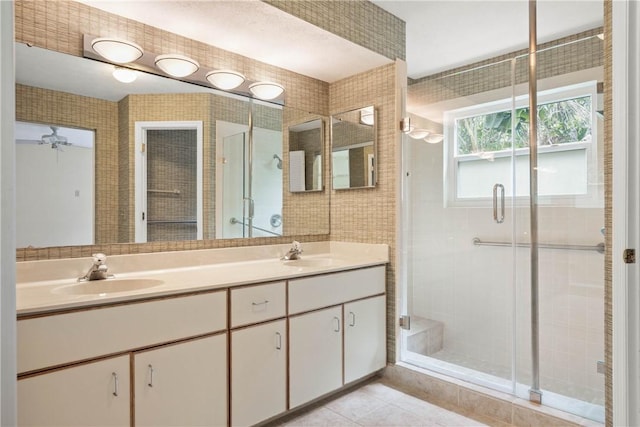 bathroom with a shower with door, vanity, tile walls, and tile patterned floors