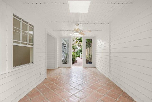 unfurnished sunroom with ceiling fan and a skylight