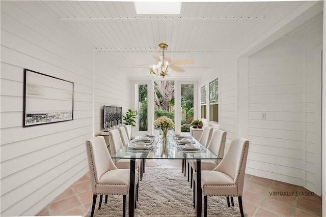 tiled dining room with wood ceiling, a skylight, wooden walls, and a chandelier