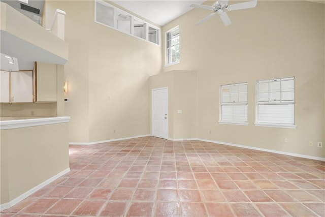 unfurnished living room with light tile patterned floors, a towering ceiling, and ceiling fan