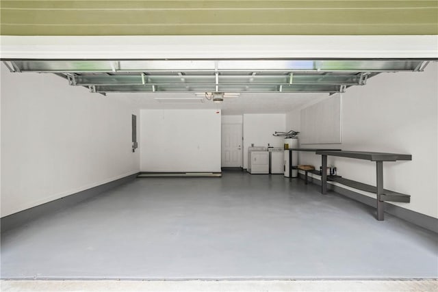 garage featuring washing machine and clothes dryer, a garage door opener, and water heater