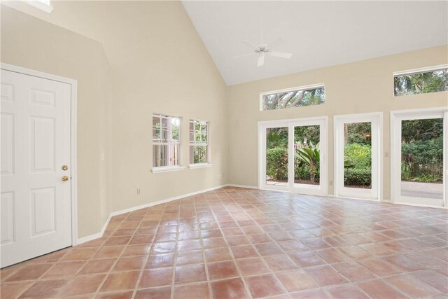 tiled empty room with ceiling fan and high vaulted ceiling