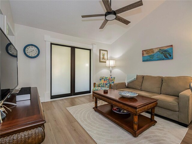 living room featuring ceiling fan, vaulted ceiling, and light wood-type flooring