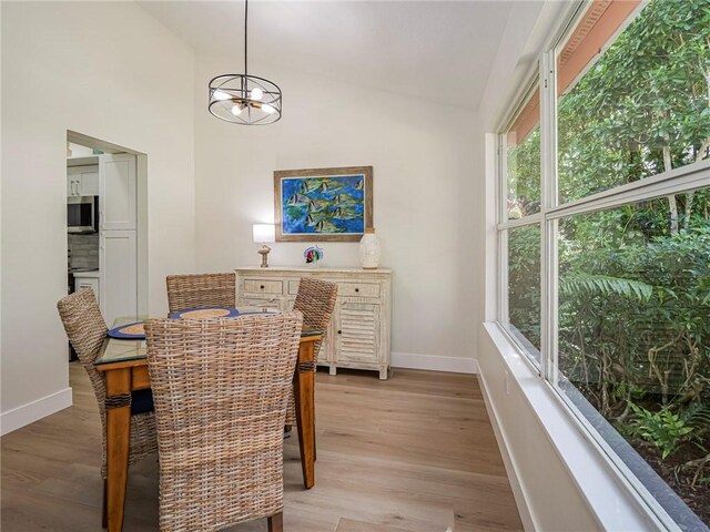 dining room featuring an inviting chandelier, high vaulted ceiling, and light hardwood / wood-style flooring