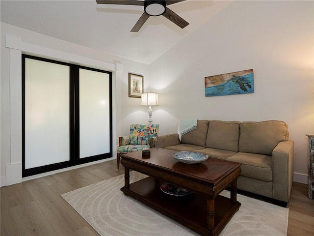 living room with light hardwood / wood-style flooring, vaulted ceiling, and ceiling fan