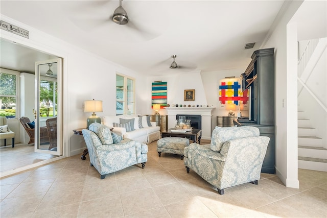 living room featuring ornamental molding, ceiling fan, light tile patterned flooring, and a fireplace