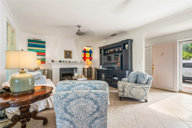 tiled living room with a fireplace, ceiling fan, and crown molding