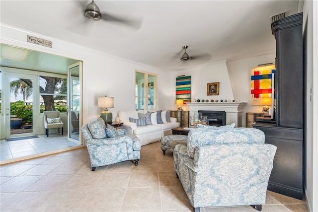 living room with ornamental molding, light tile patterned flooring, ceiling fan, and a fireplace