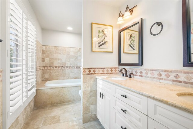 bathroom featuring tile walls, vanity, tile patterned flooring, and tiled tub