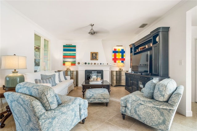 living room with a fireplace, ceiling fan, crown molding, and light tile patterned flooring