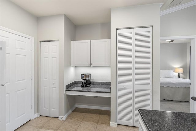 kitchen featuring light tile patterned flooring, dark stone countertops, and white cabinets