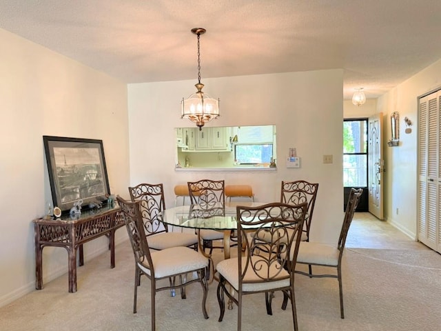 dining space with baseboards, light colored carpet, and a chandelier