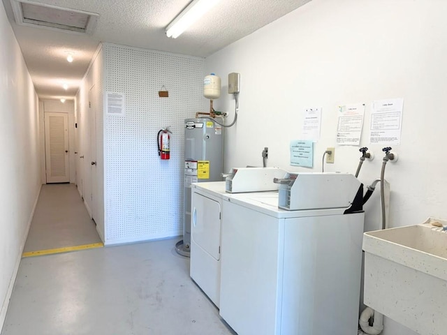 laundry room with a sink, separate washer and dryer, water heater, and a textured ceiling