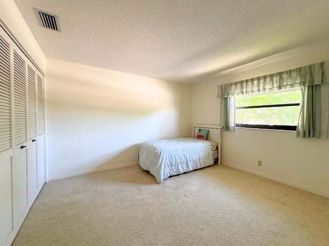 unfurnished bedroom featuring visible vents, a textured ceiling, a closet, carpet floors, and baseboards