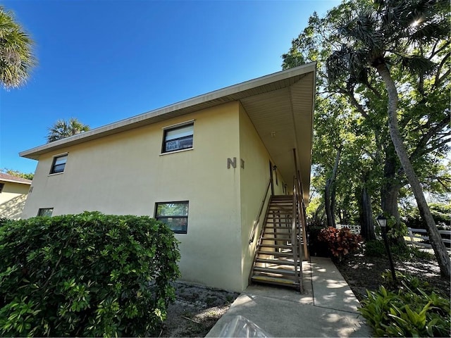 view of side of property featuring stairway and stucco siding