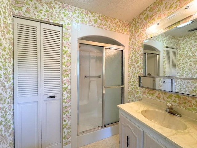 full bath featuring a closet, a textured ceiling, wallpapered walls, and a stall shower