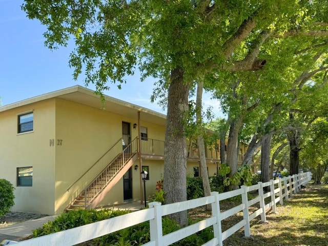 view of side of home with a fenced front yard, stucco siding, and stairs