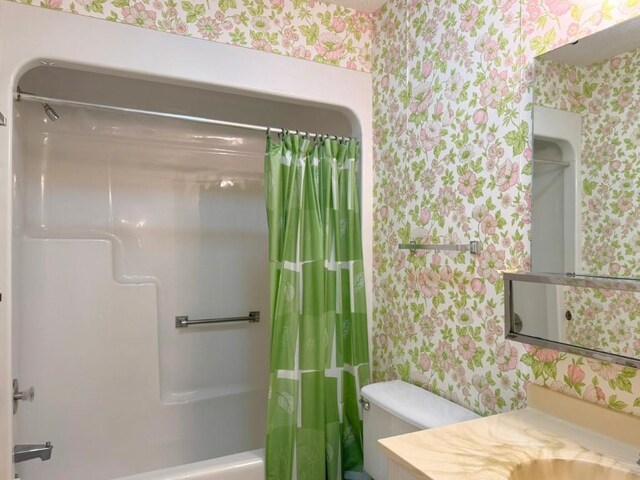 full bath featuring wallpapered walls, toilet, vanity, and shower / bath combo