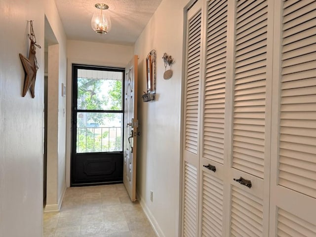 entryway with baseboards, a textured ceiling, and light tile patterned flooring