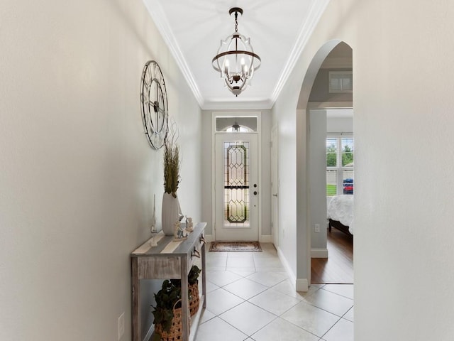 tiled foyer entrance with an inviting chandelier and ornamental molding