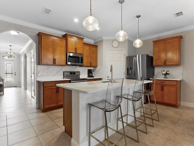 kitchen with sink, hanging light fixtures, a center island with sink, a kitchen breakfast bar, and stainless steel appliances