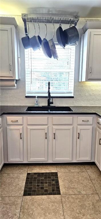 kitchen featuring light tile patterned floors, sink, and white cabinets