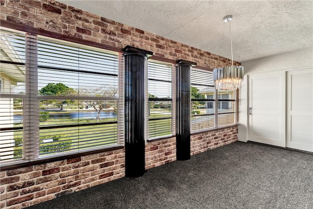 217 Grove Isle Cir Unit 217, Vero Beach, FL 32962 - unfurnished dining area featuring dark carpet, a textured ceiling, and brick wall