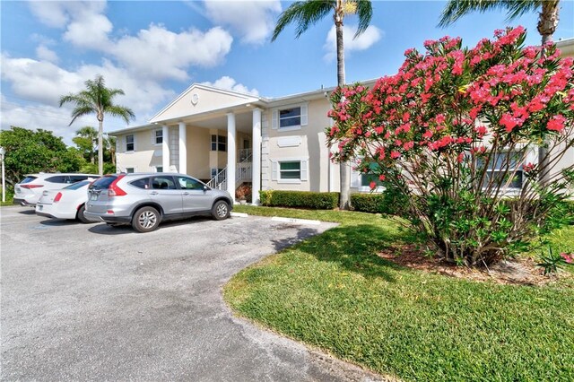 217 Grove Isle Cir Unit 217, Vero Beach, FL 32962 - greek revival house featuring stucco siding, a front lawn, and uncovered parking