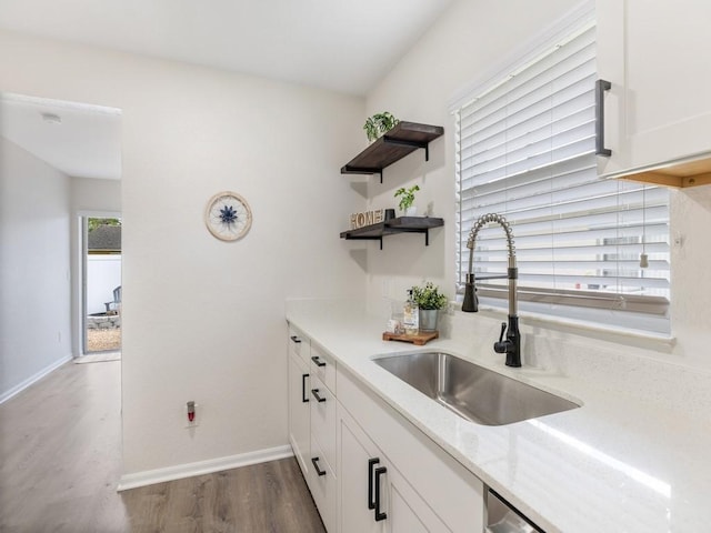 kitchen with white cabinetry, sink, and wood-type flooring