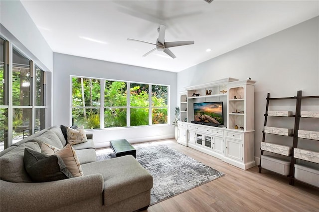 living room featuring light wood-style floors, a ceiling fan, and a wealth of natural light