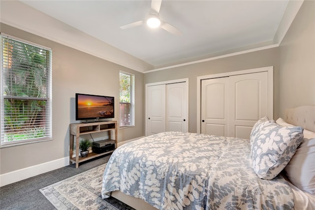 carpeted bedroom with multiple closets, ceiling fan, and baseboards