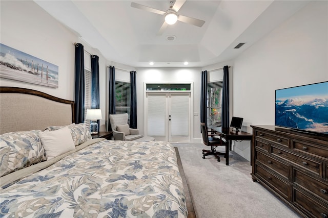 bedroom with access to exterior, a tray ceiling, light colored carpet, visible vents, and ceiling fan