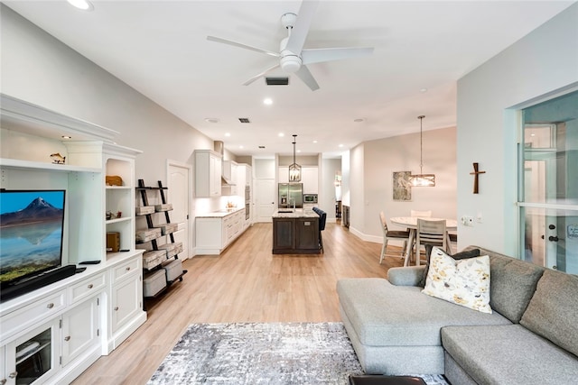 living area featuring baseboards, recessed lighting, a ceiling fan, and light wood-style floors