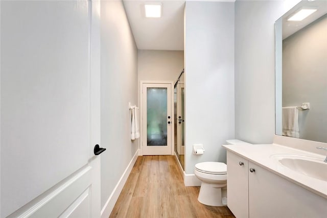 bathroom with vanity, wood finished floors, toilet, and baseboards