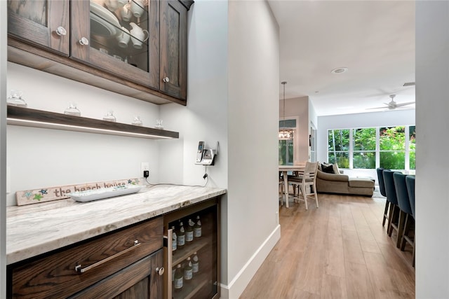 bar with beverage cooler, visible vents, baseboards, a ceiling fan, and light wood-style flooring