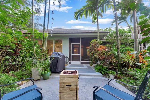 view of patio / terrace with a fire pit, a grill, and a sunroom