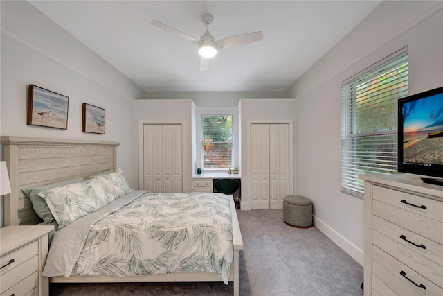 bedroom featuring carpet, two closets, a ceiling fan, and baseboards