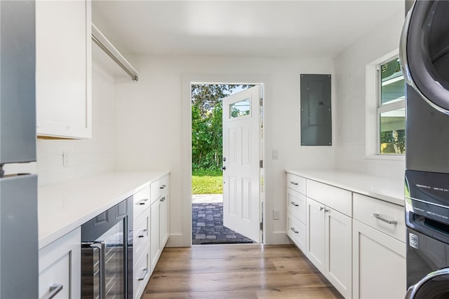 kitchen featuring wine cooler, stacked washing maching and dryer, electric panel, and light hardwood / wood-style floors