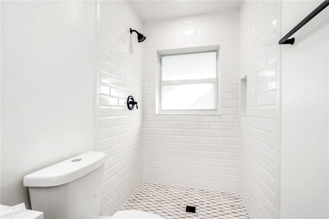 bathroom featuring toilet and a tile shower