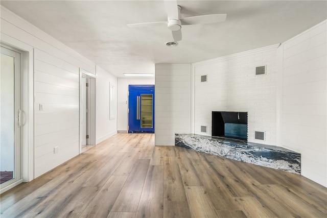 unfurnished living room featuring light wood-type flooring, ceiling fan, and a fireplace