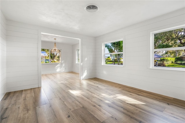 unfurnished room featuring light hardwood / wood-style flooring and wooden walls