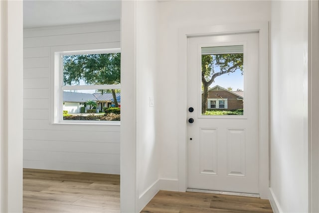 doorway to outside featuring light wood-type flooring and wooden walls