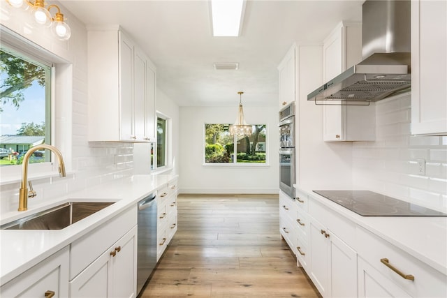 kitchen featuring light hardwood / wood-style floors, sink, appliances with stainless steel finishes, white cabinets, and wall chimney range hood